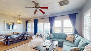 A living room with a ceiling fan, a dining area with a wooden table, and a sofa with decorative pillows.