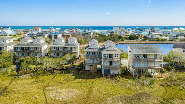 A coastal residential area with multiple two-story houses, some with balconies, and a view of the ocean.