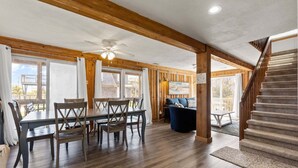 A spacious room with a dining table, chairs, a sofa, and a staircase.