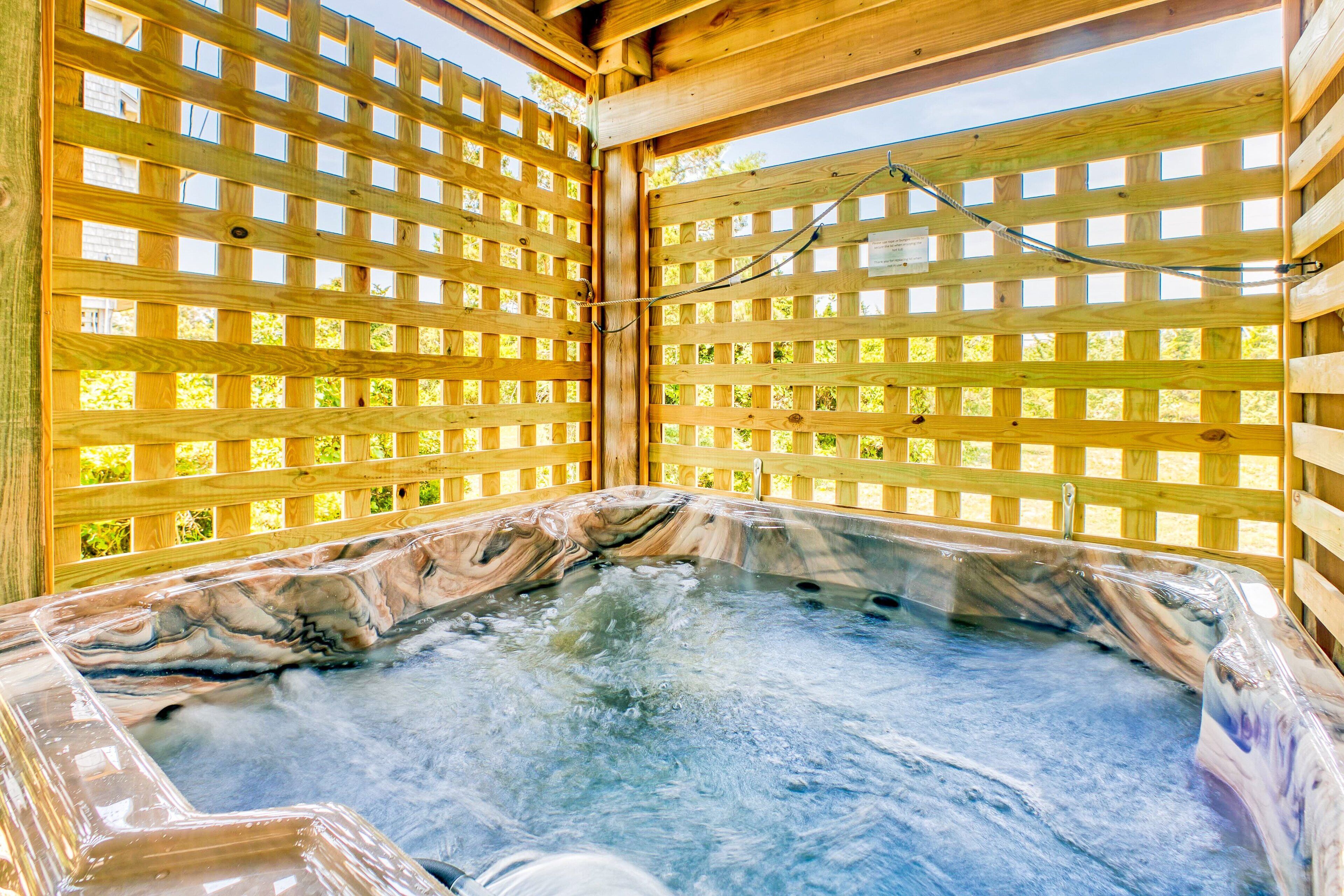 A hot tub with a wooden lattice enclosure, surrounded by a wooden deck.