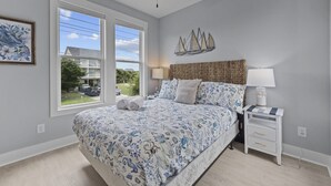 A bedroom with a large bed, a ceiling fan, a nightstand with a lamp, and a window with a view of the outside. - Stunning sound view home, close to the beach in the heart of Surf City (Surf City)