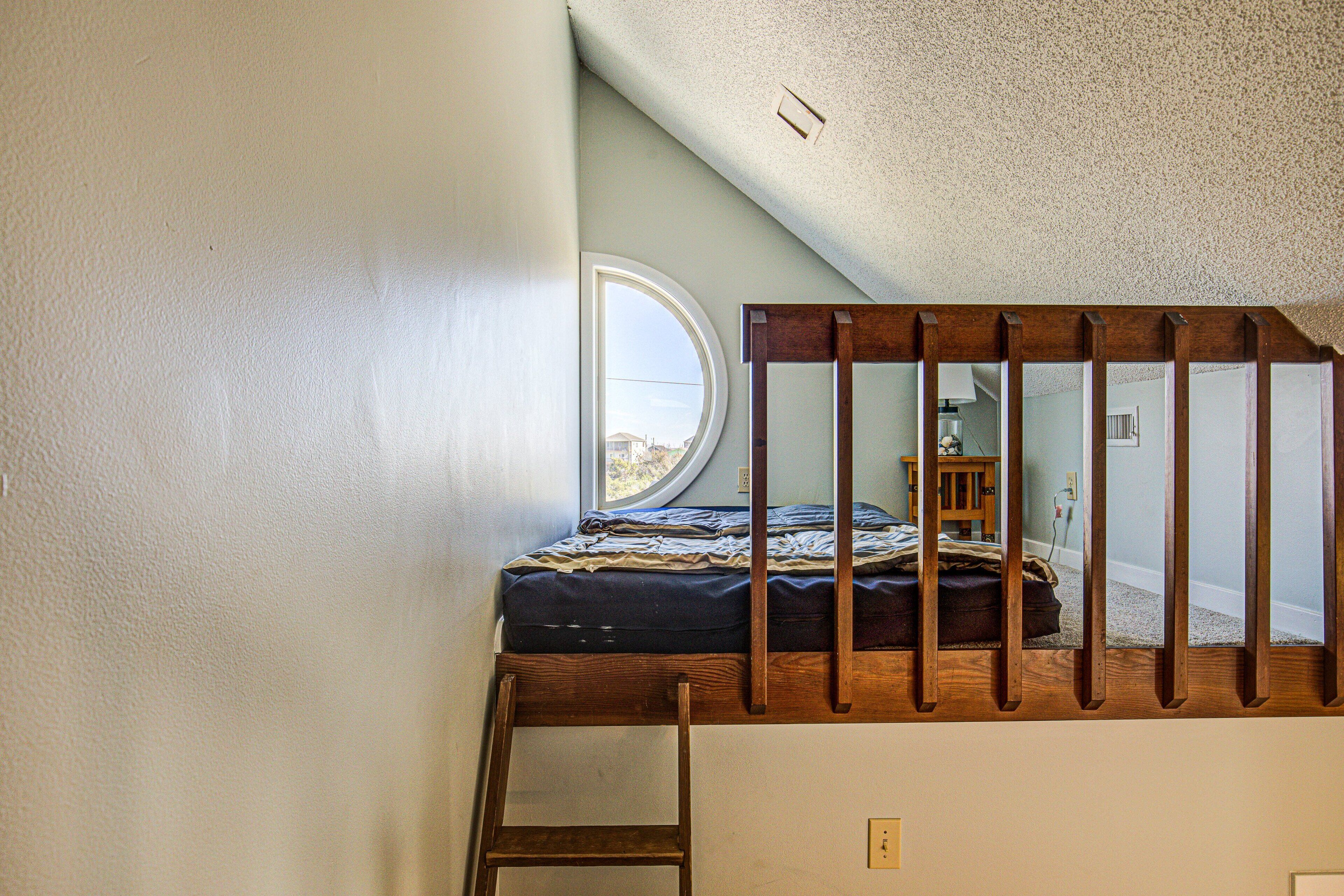 A small room with a bunk bed, a window, and a wooden ladder.