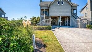 A two-story house with a front porch, a staircase leading to the second floor, and a well-maintained lawn. - Ocean and waterway-view duplex - pool, beach access, washer/dryer, central AC (Topsail Beach)