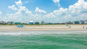 A beach with houses in the background and a clear sky. - Oceanfront home with beach access, a game room, washer/dryer, & central AC (Topsail Beach)