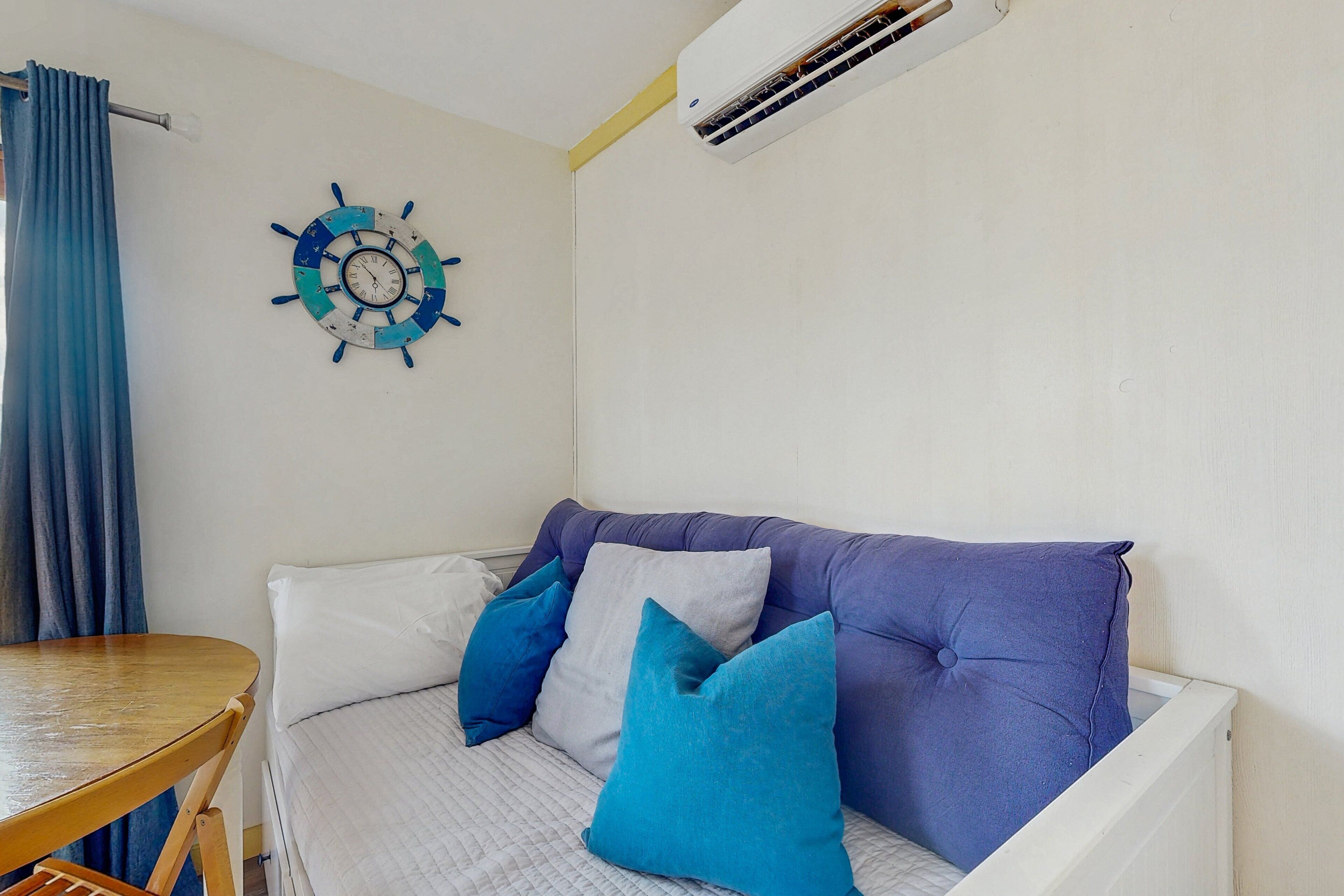 Una habitación con cama, una mesa y aire acondicionado instalado en la pared.