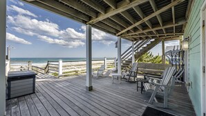 A wooden deck with outdoor seating, overlooking a beach. - Beachfront home with stunning views, elevator and multiple decks (Topsail Beach)