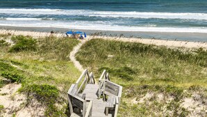 A wooden boardwalk leading to a beach with a clear view of the ocean. - Casablanca: Avon beach escape with themed suites, pool, hot tub & ocean views. (Avon)