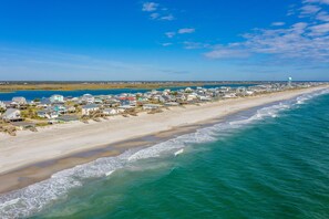 A coastal town with beachfront properties and a lighthouse in the distance. - Dog-friendly home with ocean views, beach access, washer/dryer & central AC (Topsail Beach)