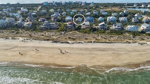 Luftaufnahme einer Küstenwohngegend mit Häusern, einem Strand und Ozeanwellen.