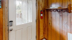 Eine Holztür mit Fenster, ein an der Wand befestigter Feuerlöscher und ein kleines Regal über der Tür.