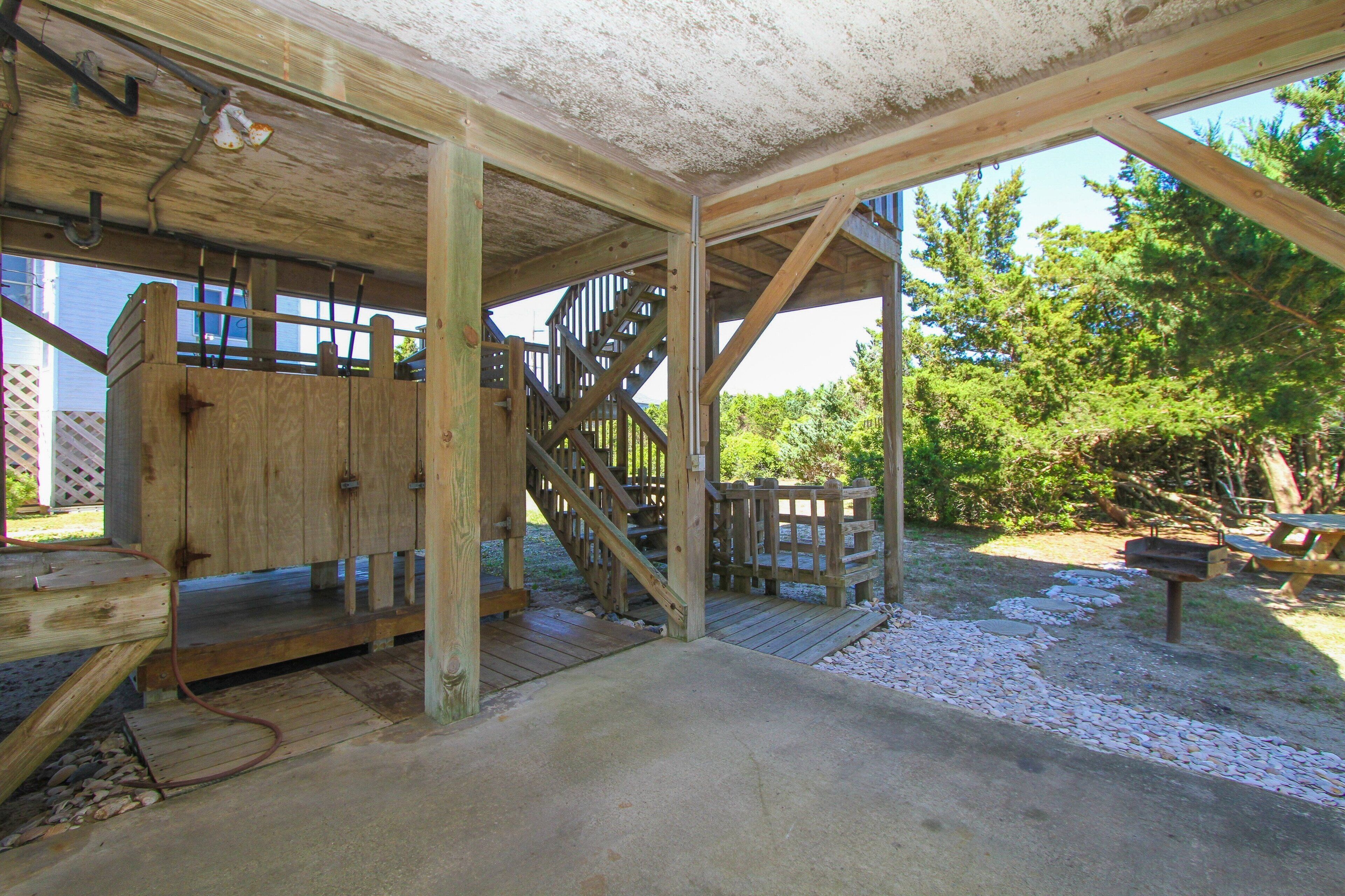 A wooden structure with a concrete floor, a wooden staircase, and a metal gate.
