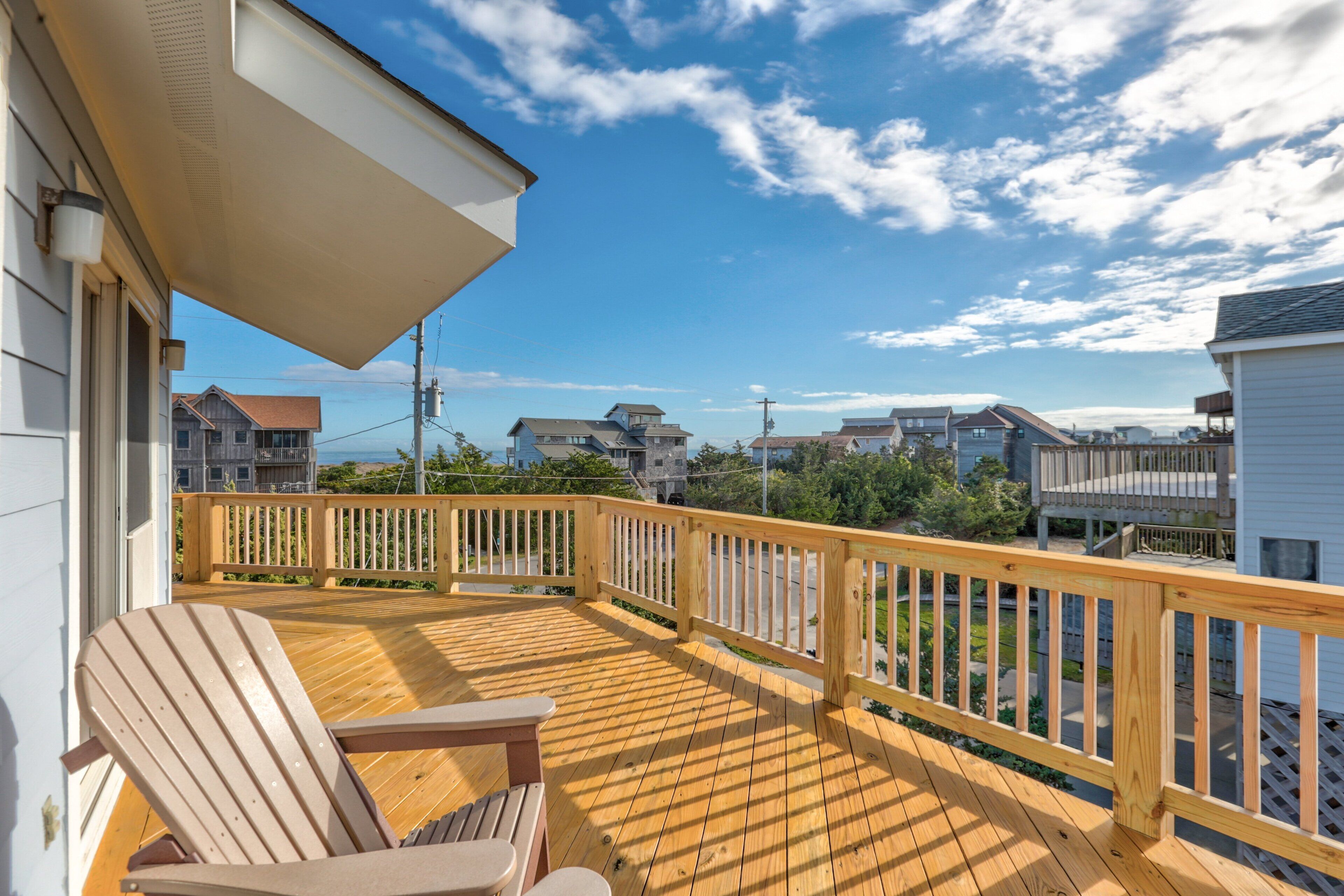 A wooden deck with a railing, a chair, and a table.