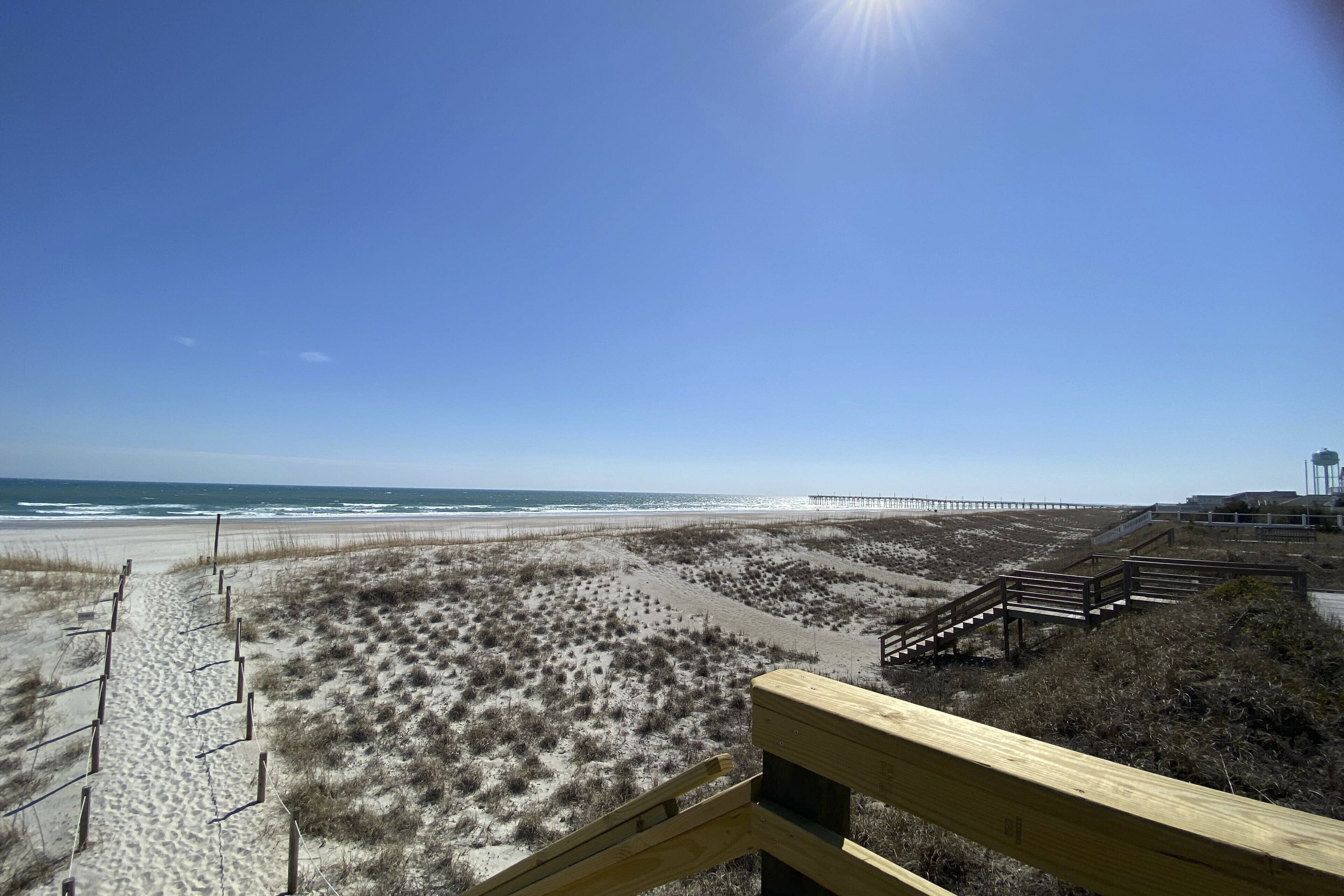 A beach with a wooden walkway leading to a pier.