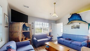 A living room with two blue sofas, a wooden coffee table, and a large fish sculpture on the wall. - Coastal home with large deck, close to beach and local attractions (Topsail Beach)
