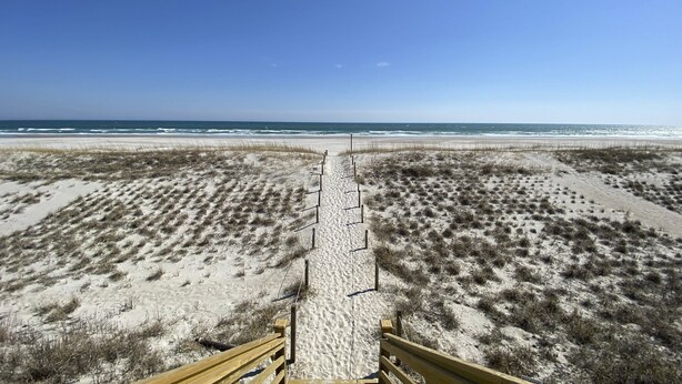 A sandy beach with a wooden boardwalk leading to the ocean. - Coastal home with large deck, close to beach and local attractions (Topsail Beach)