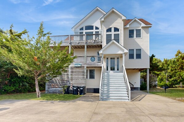 A two-story building with a balcony, a staircase leading to the entrance, and a sign indicating a restaurant. - Beach home with private hot tub, pool, sound view & game room - dog-friendly (Waves)