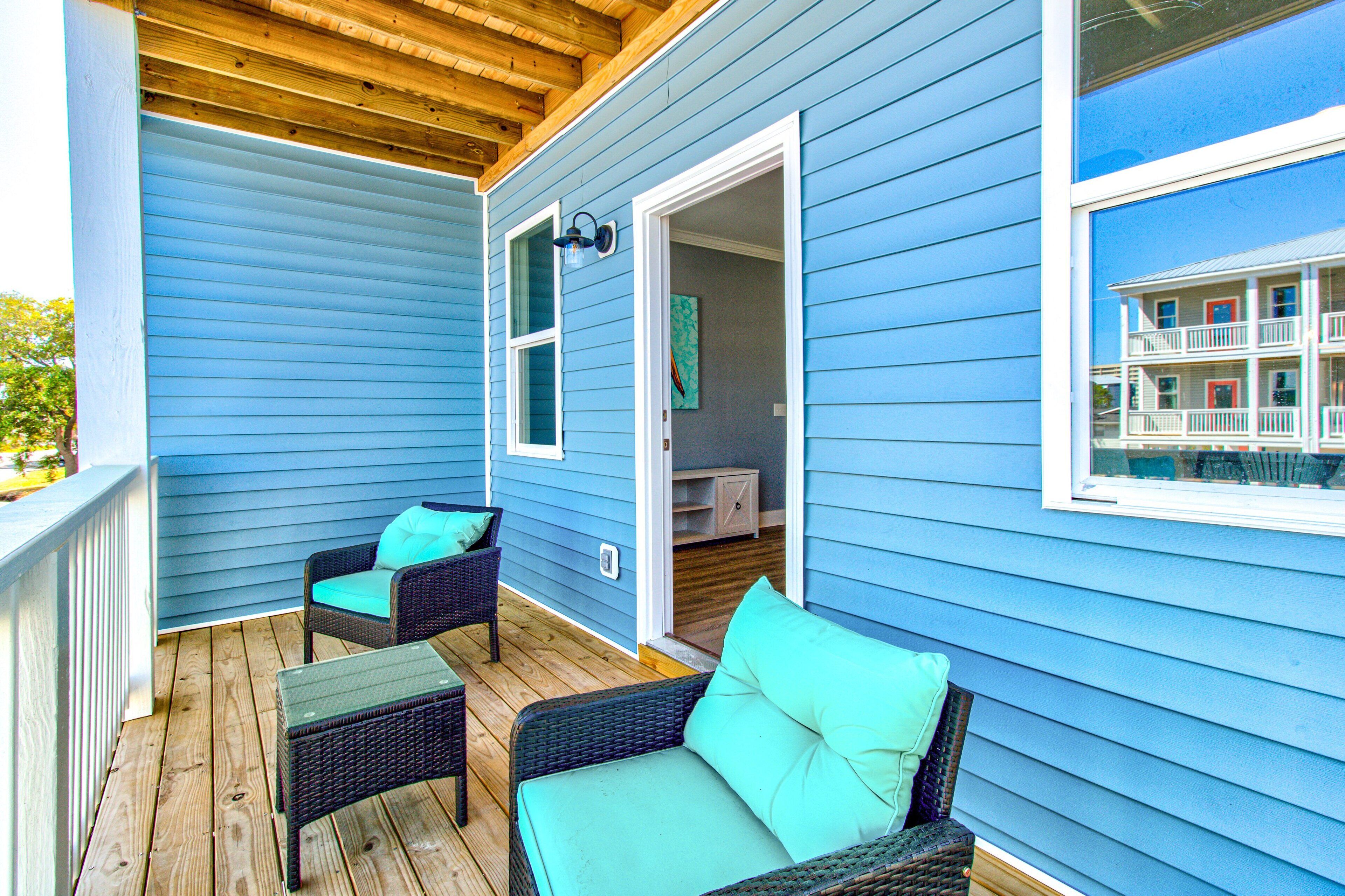 A covered porch with wicker furniture and a view of a multi-story building.