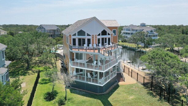 A multi-story waterfront property with a balcony, a dock, and a view of the water. - Waterfront home with ocean views, private pool, hot tub, & Tesla/EV charger (Frisco)