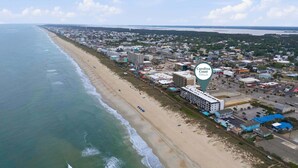 Ilmakuva rannikkokaupungista, jossa näkyy ranta, rakennuksia ja merkki, jossa lukee: »Carolina Coast Retreats».