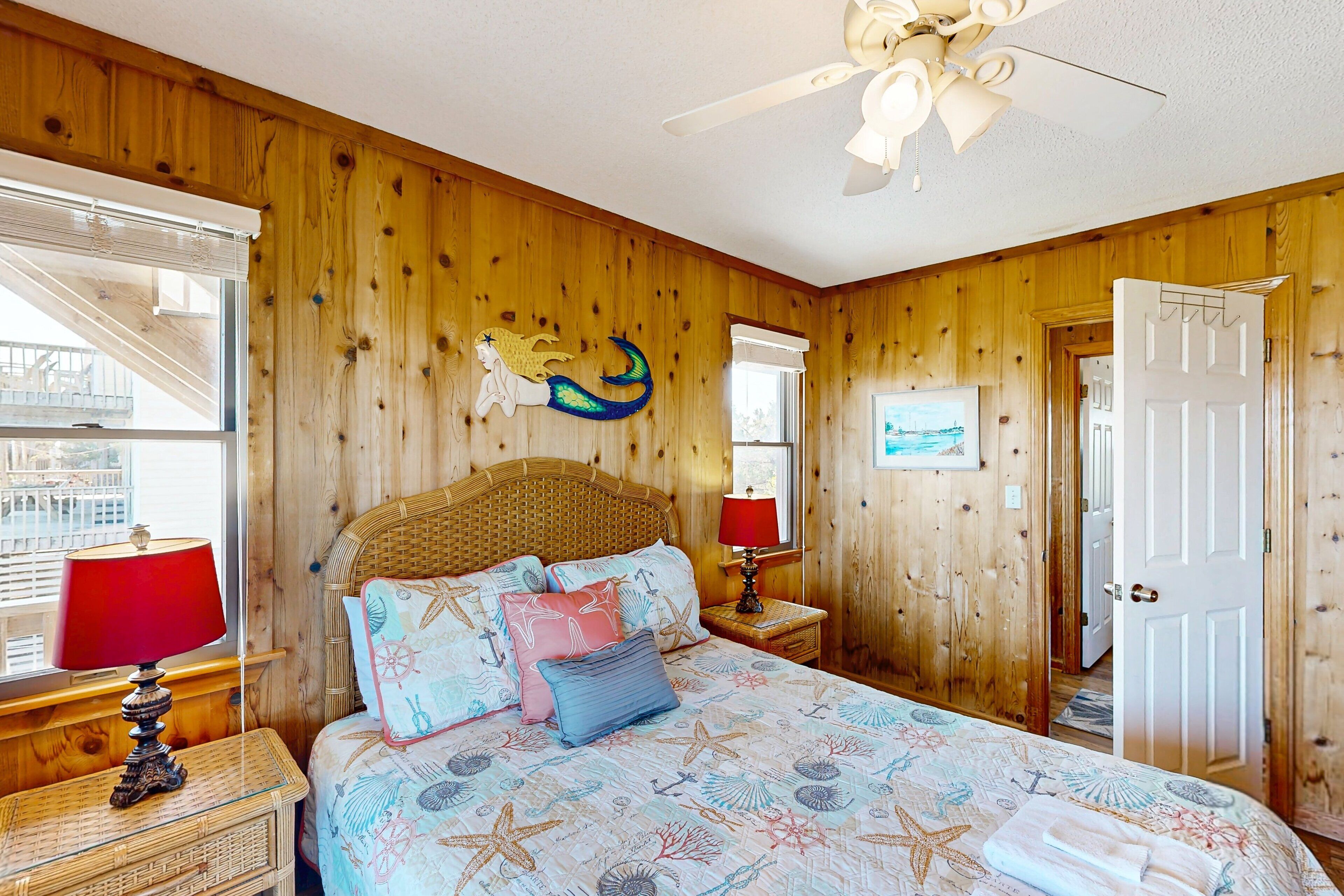 A wooden-paneled bedroom with a bed, nightstands, a ceiling fan, and a window with blinds.