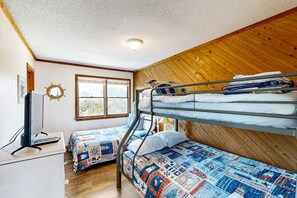 Une chambre de dortoir avec des lits superposés, un bureau avec un ordinateur, une fenêtre et un plafond en bois.