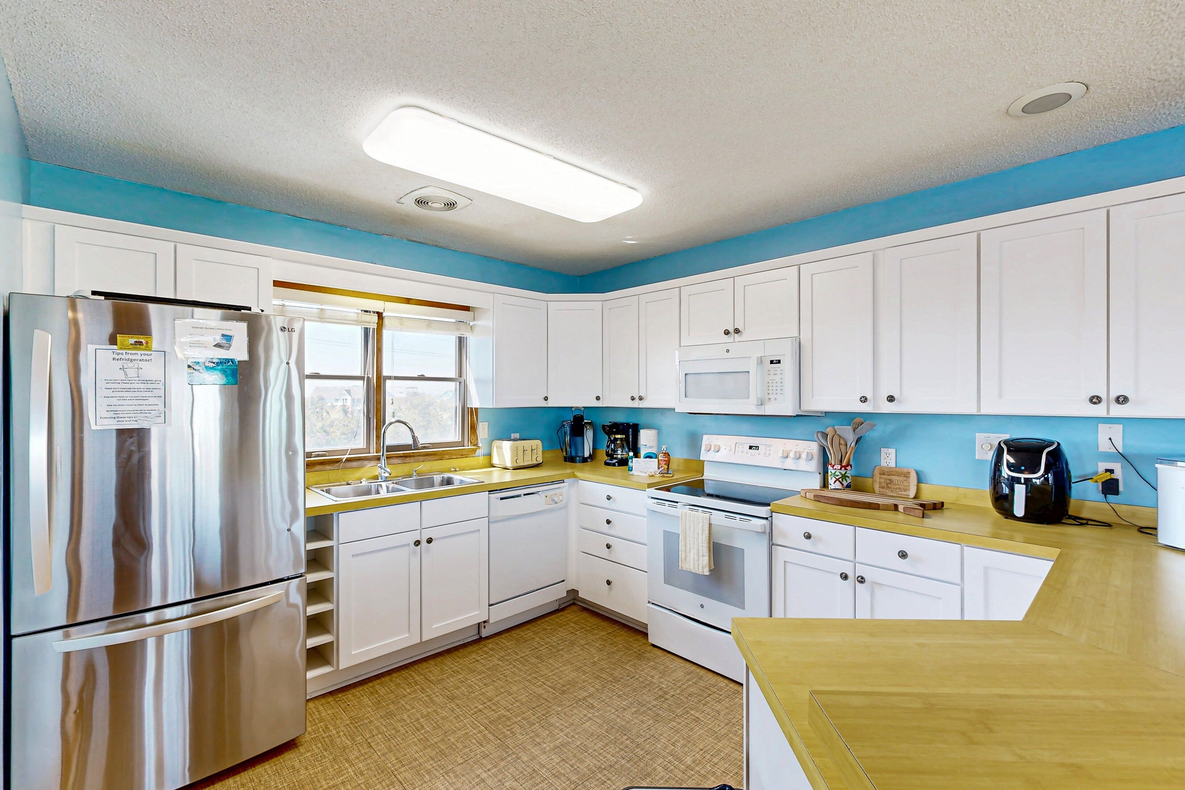 A modern kitchen with white cabinets, stainless steel appliances, and a yellow countertop.
