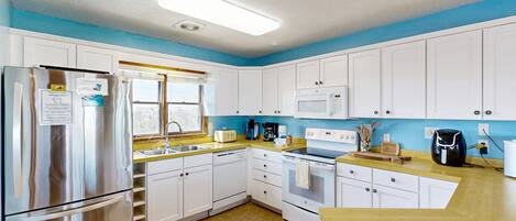 A modern kitchen with white cabinets, stainless steel appliances, and a yellow countertop.