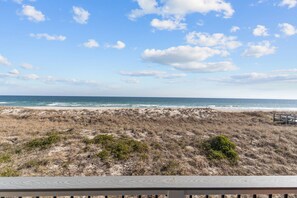 Une plage avec une terrasse en bois et une vue sur l’océan.