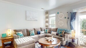 A cozy living room with a sectional sofa, a round coffee table, and nautical-themed decor.