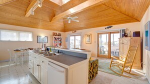 A spacious kitchen with a large island, wooden ceiling beams, and a ceiling fan. - Sea Dream 440: Lagoon-front home w/private dock (Avon)