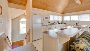 A kitchen with wooden ceiling, white cabinets, a refrigerator, microwave, and a large island with a sink. - Sea Dream 440: Lagoon-front home w/private dock (Avon)