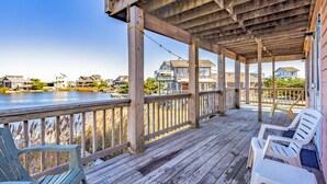 A wooden deck with chairs overlooking a body of water and houses in the background. - Sea Dream 440: Lagoon-front home w/private dock (Avon)
