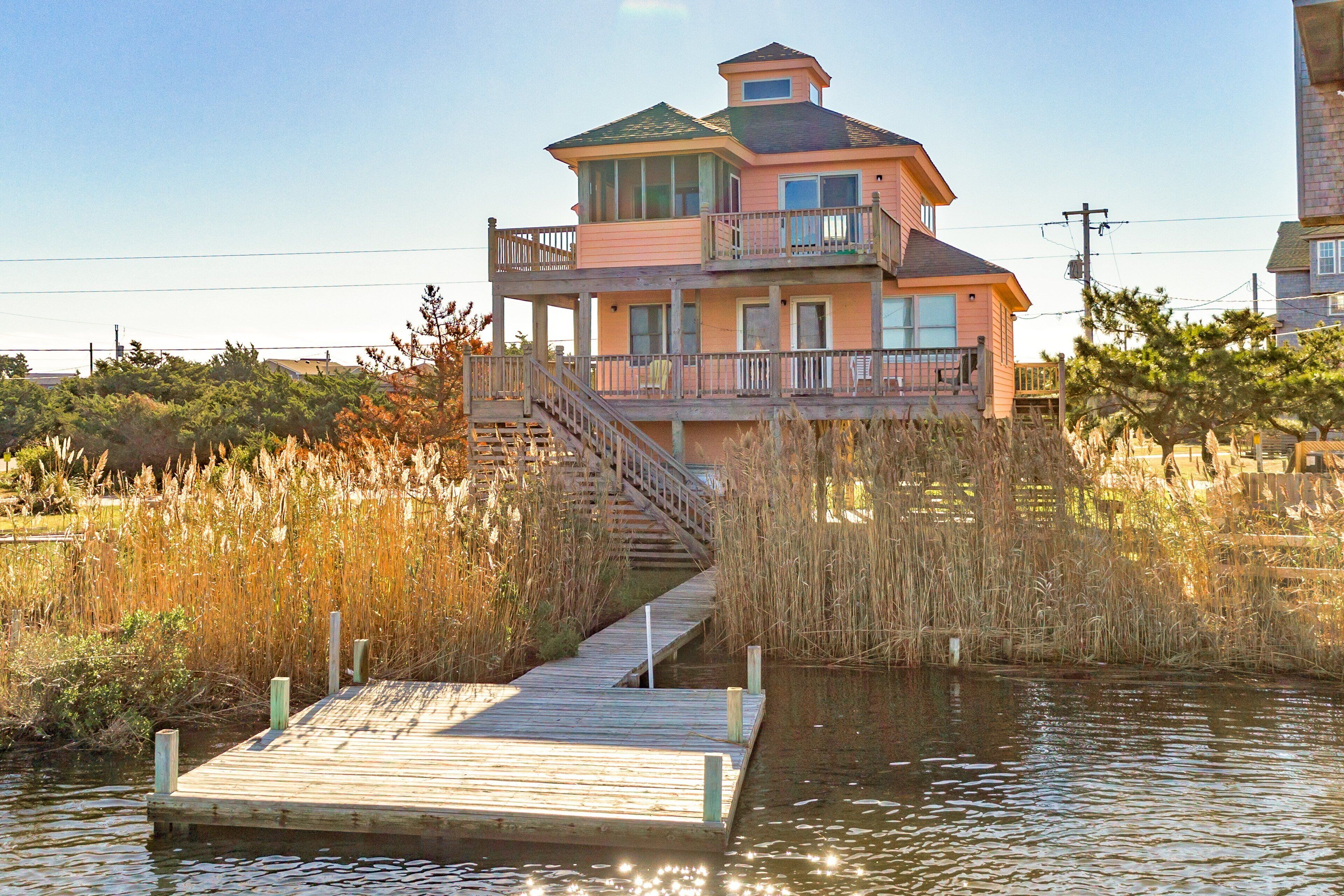 A two-story house with a balcony and a wooden dock extending into a body of water.