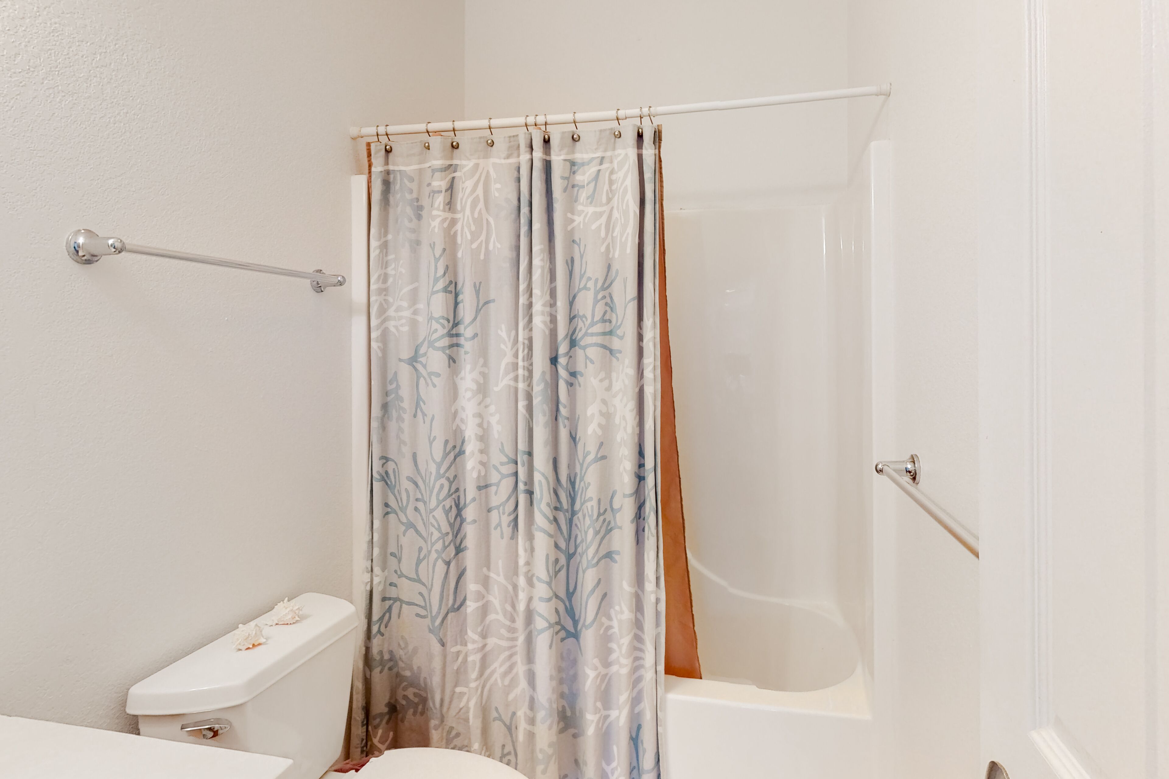 A bathroom with a toilet, a shower curtain, and a bathtub.