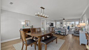 A spacious living area with a wooden dining table, benches, and a chandelier. - Canal front home with a floating dock and large deck with sound views (Topsail Beach)