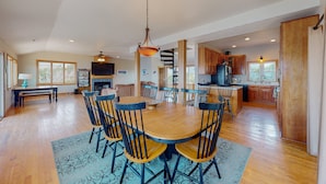 A spacious kitchen with wooden cabinets, a central island, and a dining area with a round table and chairs. - Waterfront home with pool, private hot tub, ocean view, W/D & AC - dog-friendly (Frisco)