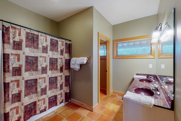 Une salle de bain avec un rideau de douche, deux lavabos et un miroir.