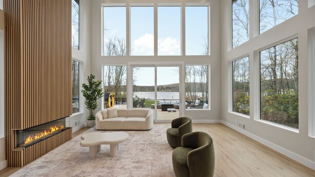 A spacious living room with a fireplace, large windows, and a view of the outdoors.