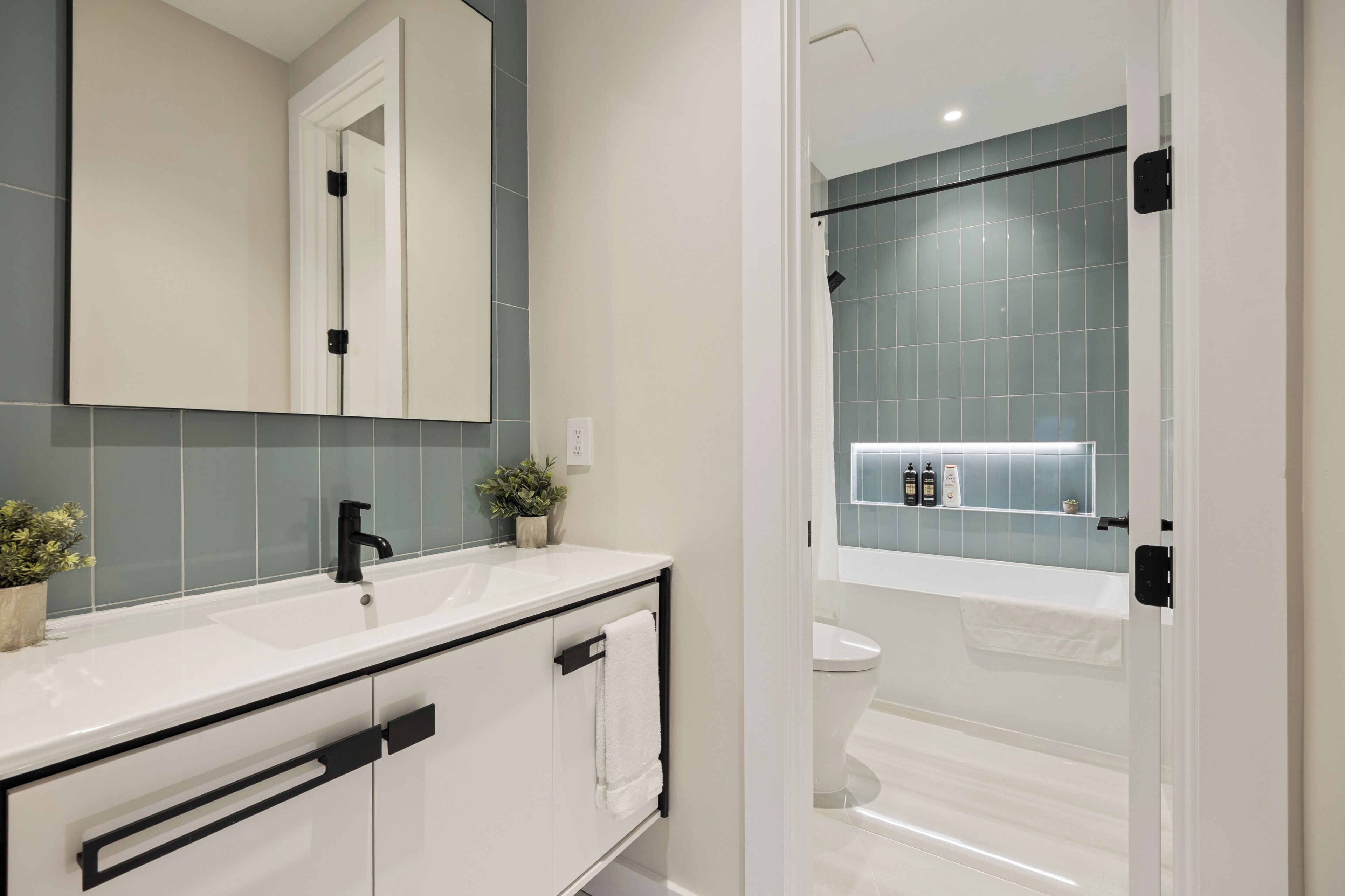 Un baño moderno con tocador blanco, grifo negro y cabina de ducha de vidrio.