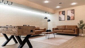 Una sala de estar moderna con una mesa de centro de madera, dos sofás y una mesa de fútbol.