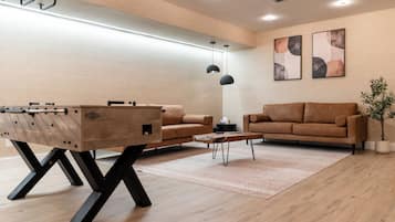 A modern living room with a wooden coffee table, two sofas, and a foosball table.