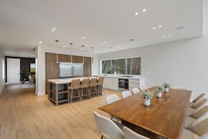 A modern kitchen with a central island, wooden cabinets, and a large window. - Lakefront Paradise w/Pool, Hot Tub, Sauna & Kayaks (Woodridge)