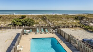 A pool area with lounge chairs and a wooden deck overlooking the beach. - Lovely beachfront condo with beach access, central AC, washer/dryer & fast WiFi (Carolina Beach)