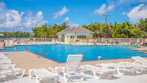 A swimming pool with lounge chairs and a small building, surrounded by trees. - Sea Escape 25: Beachfront, dog-friendly, private hot tub (Avon)