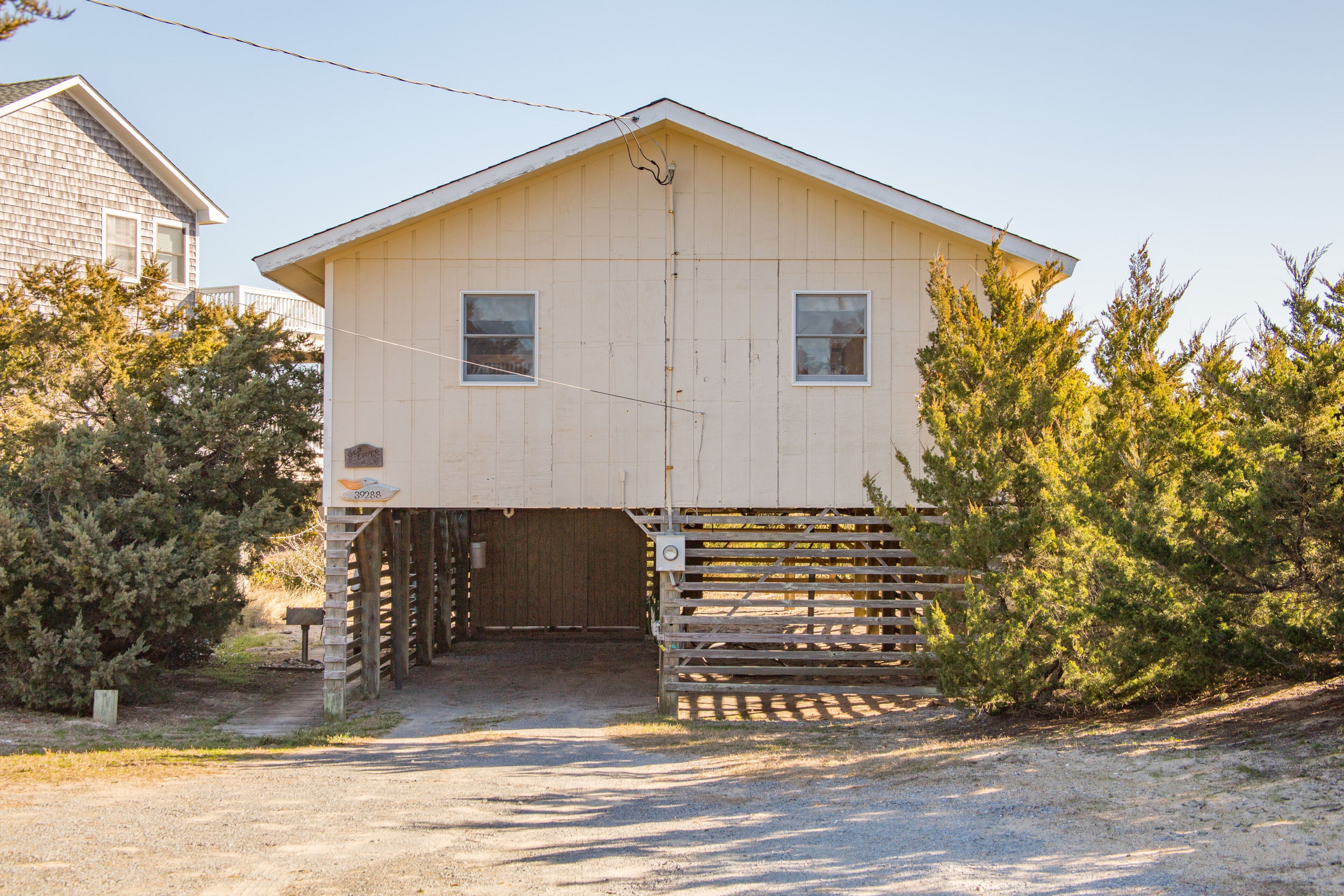 A two-story building with a garage entrance, wooden fence, and surrounding vegetation.