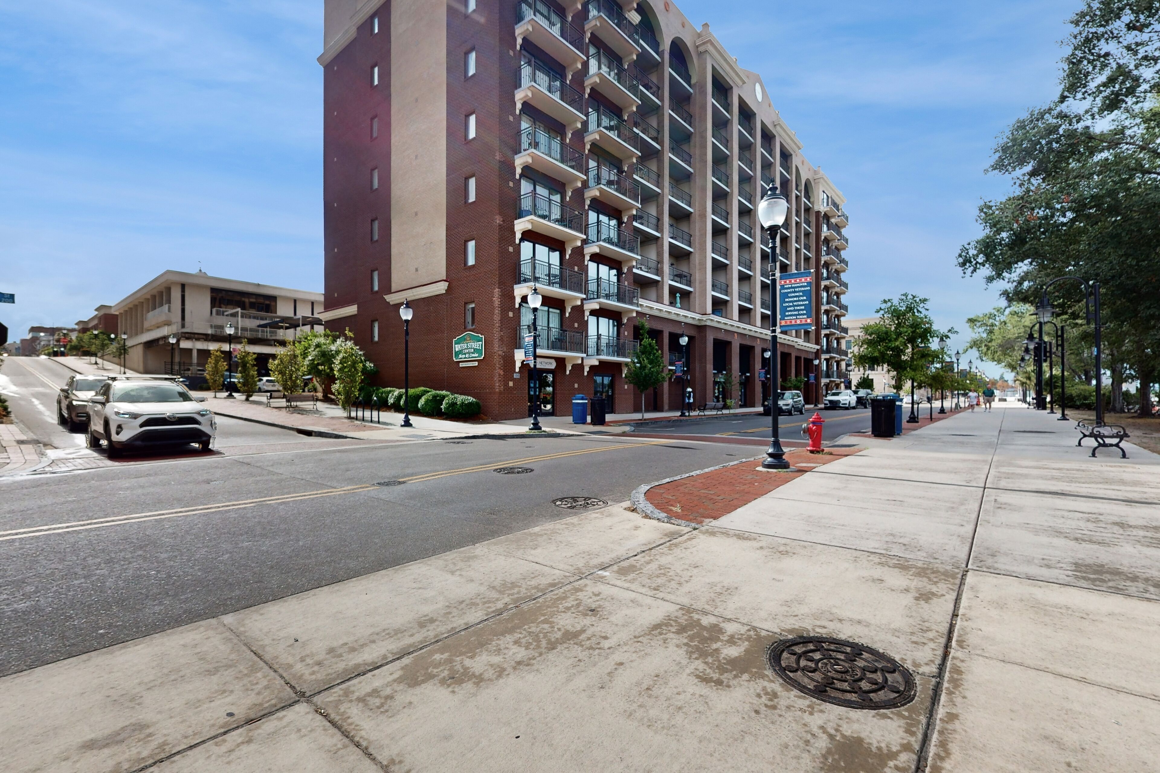 A multi-story hotel with a brick facade, multiple balconies, and a street view.