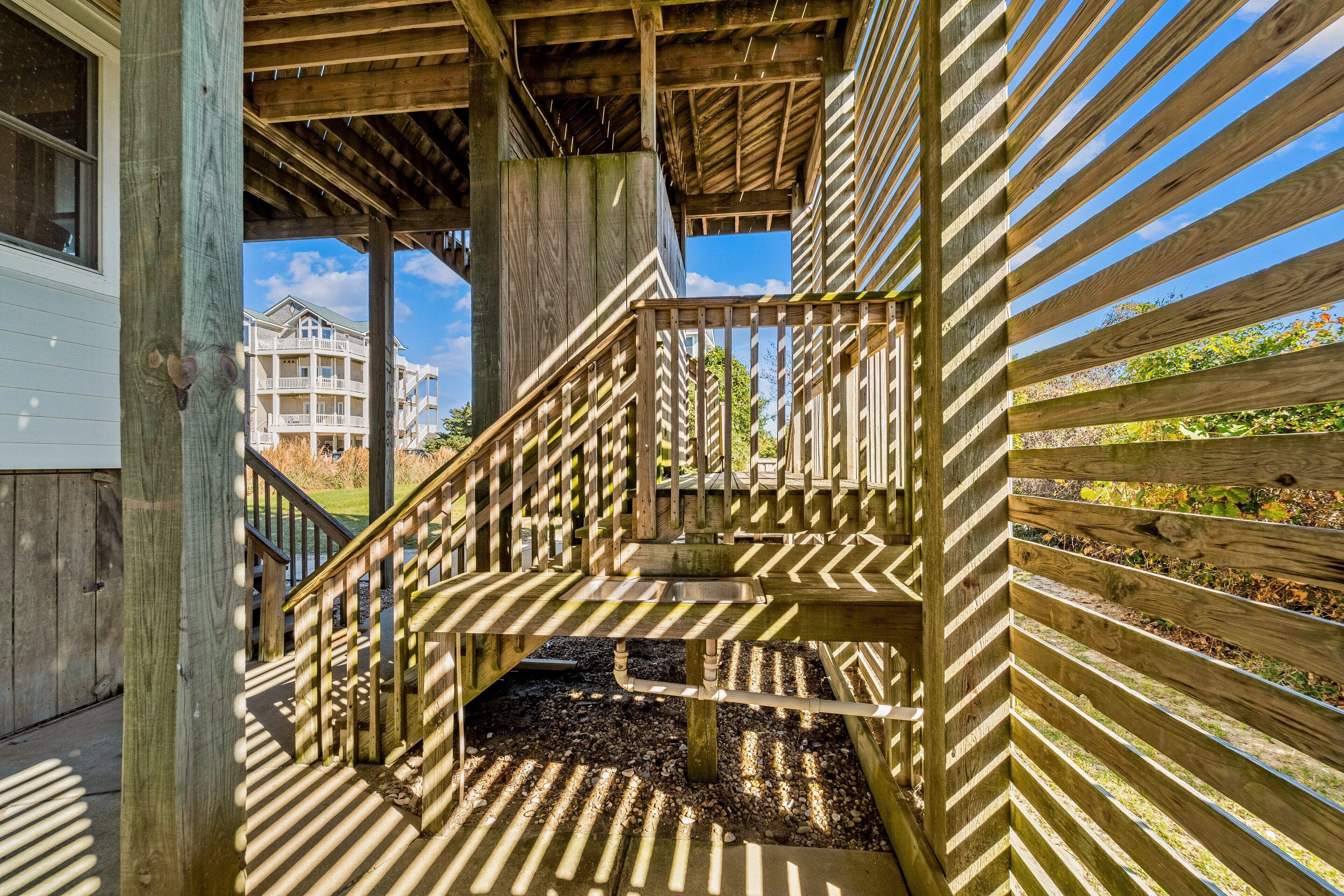 A wooden staircase with a metal handrail leading to a covered outdoor area.