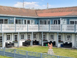 A two-story building with a balcony, multiple windows, and outdoor seating areas. - 5 Star Holiday Home in Dannemare (Dannemare)