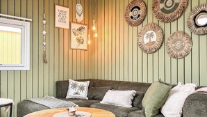 Ein gemütliches Wohnzimmer mit einer grün gestreiften Wand, einem grauen Sofa und einem runden Couchtisch aus Holz.