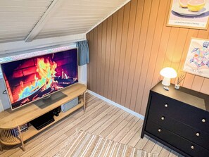 A cozy room with a flat-screen TV on a wooden stand, a black dresser, and a framed picture on the wall. - 6 Person Holiday Home in Vaeggerlose (Vaeggerlose)